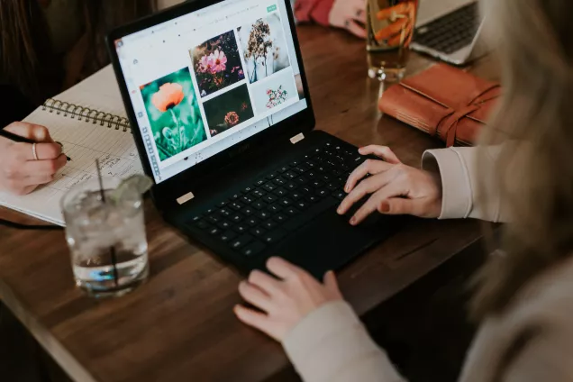 Foto av några studenter som grupparbetar framför en laptop.